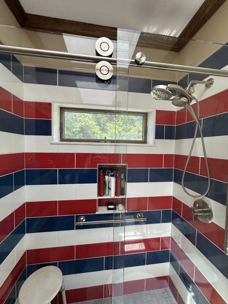 Custom striped shower tile installation with red white and blue tile design