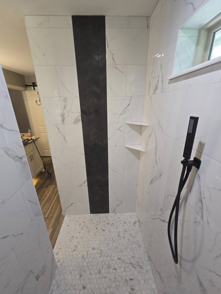 Large format marble shower tile installation with shower niche