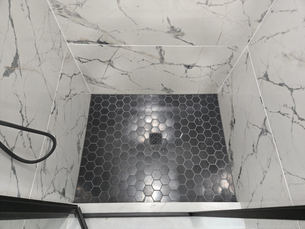 Hexagon shower floor tile installation with marble shower walls by JPond Custom Tile