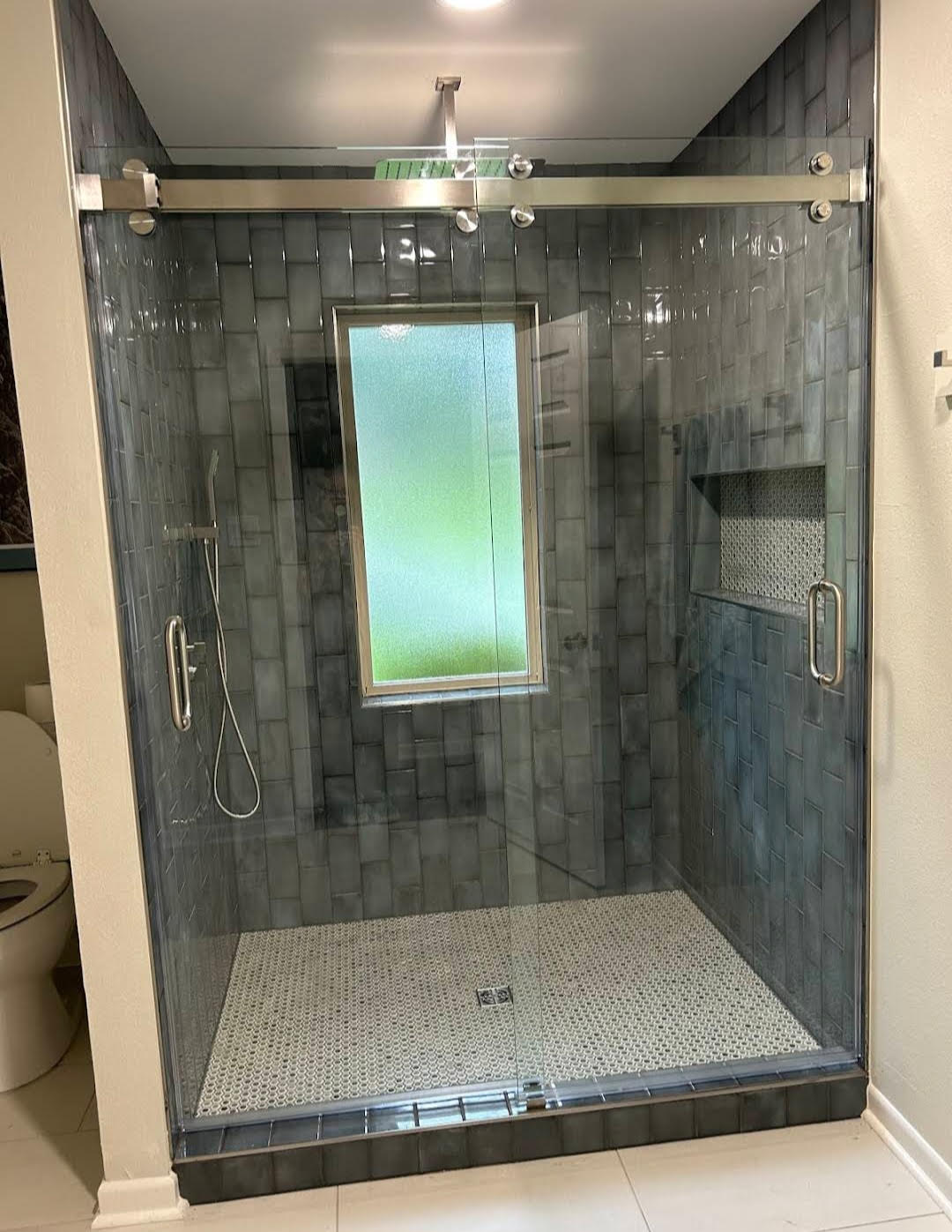 Walk-in shower tile installation with glass enclosure by JPond Custom Tile